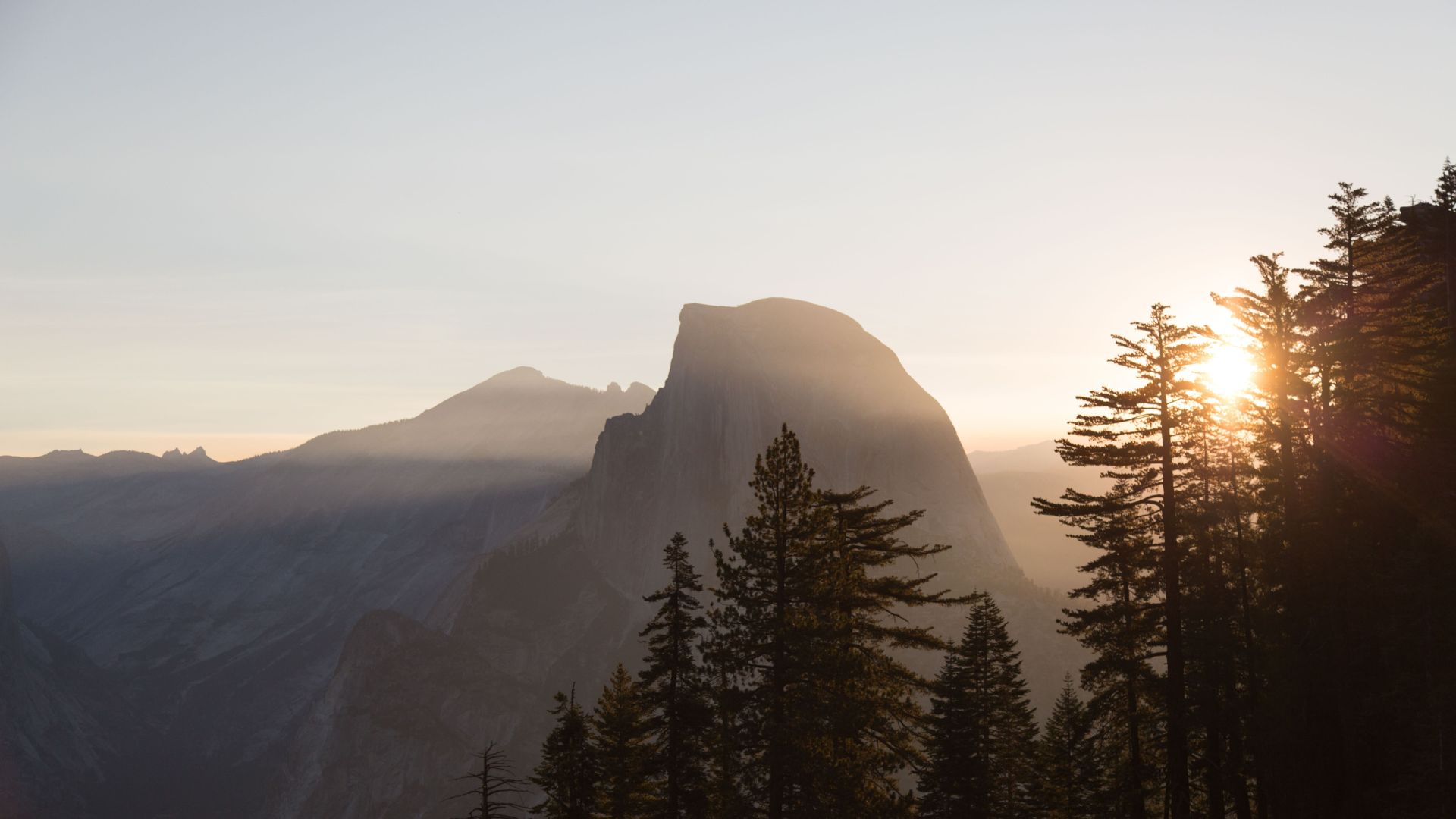 Lever de soleil derrière une montagne et une forêt de sapins